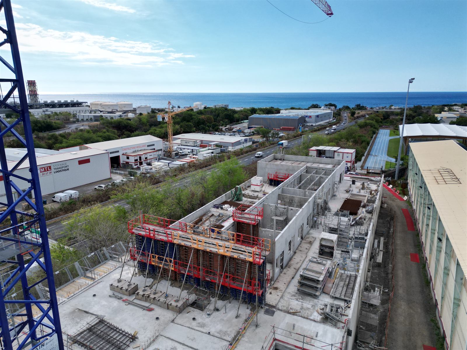 Le bâtiment en construction avec la grue bleue et l'océan en arrière-plan