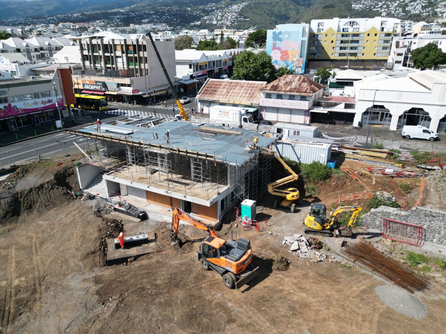 Bâtiment en cours de couverture, avec la ville et les montagnes en arrière-plan